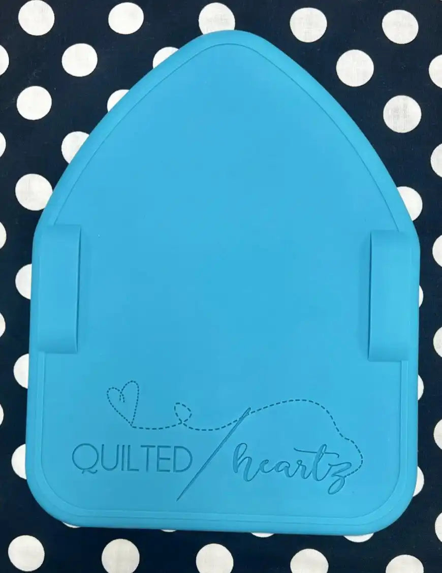 Light blue house-shaped design with ’Quilted hearts’ text and a heart doodle.